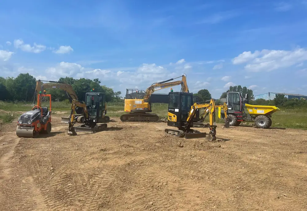 A line of plant drawn up across an open training area: mini excavators, a tracked 360-degree excavator, a wheeled excavator and a forward tipping dumper