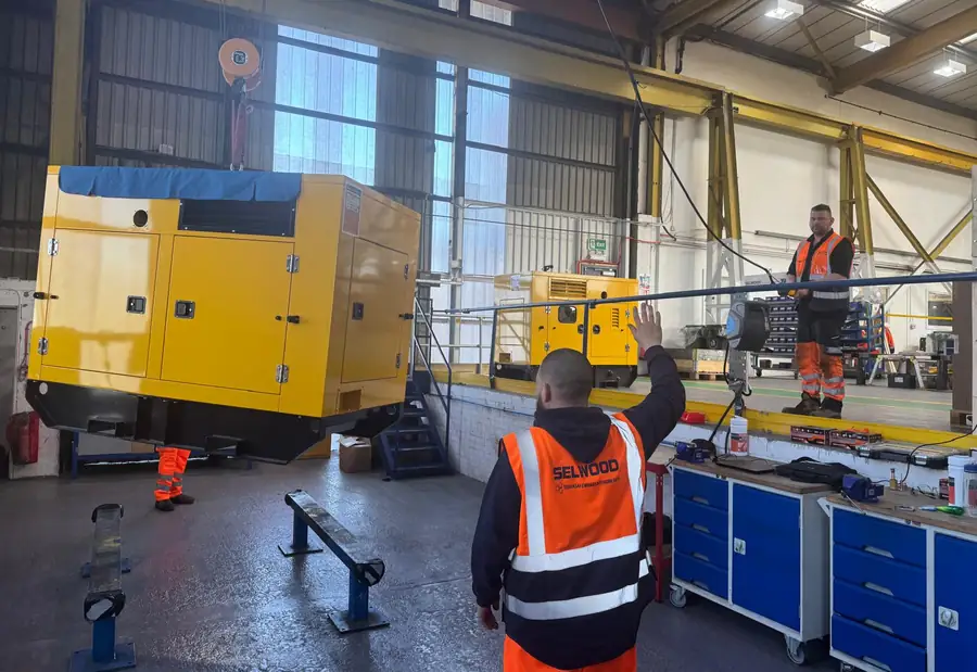 People in hi-vis around generator units on a workshop floor during a session at a customer's premises